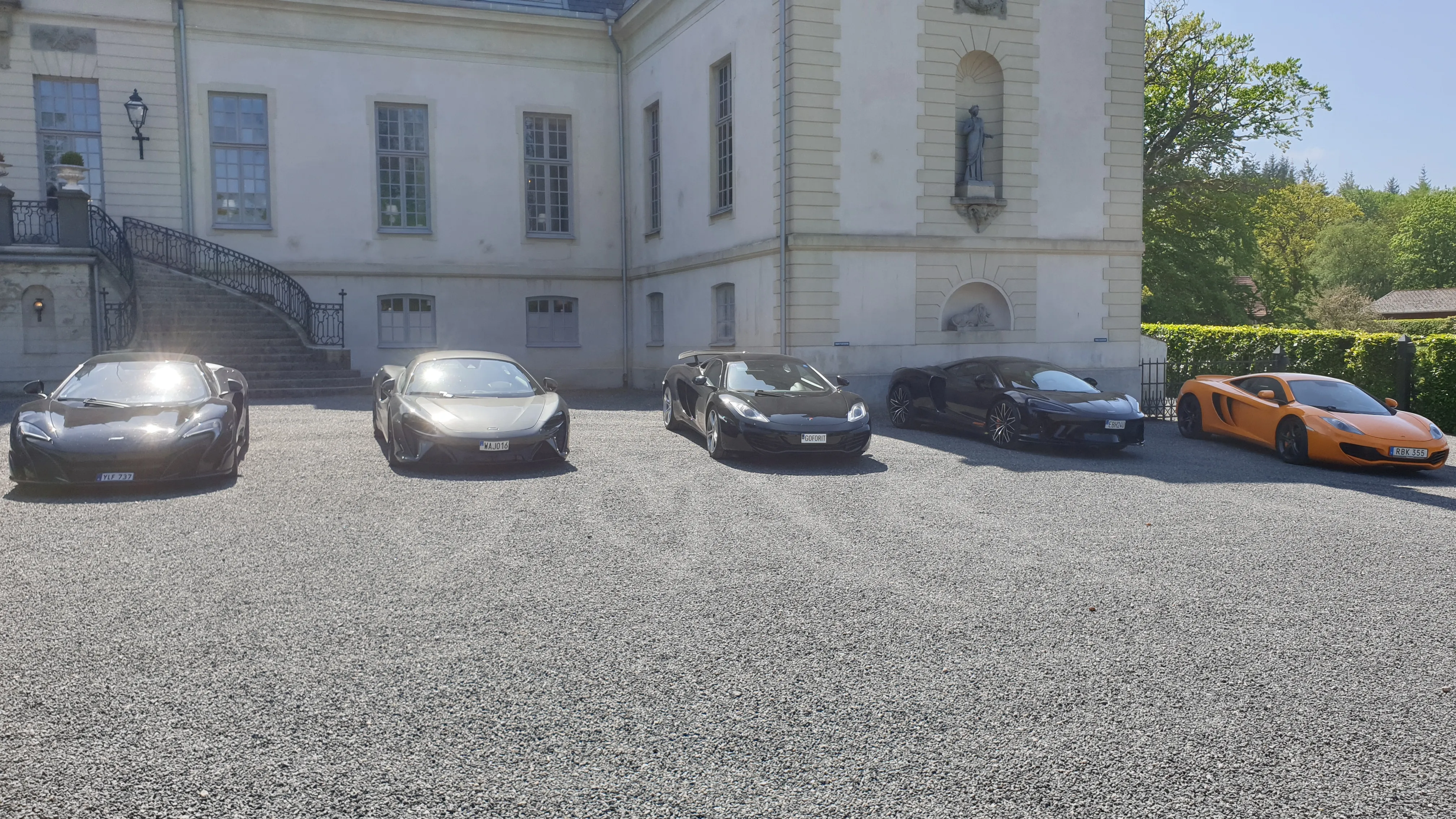 Flera McLaren-bilar parkerade framför en herrgårdsbyggnad.
